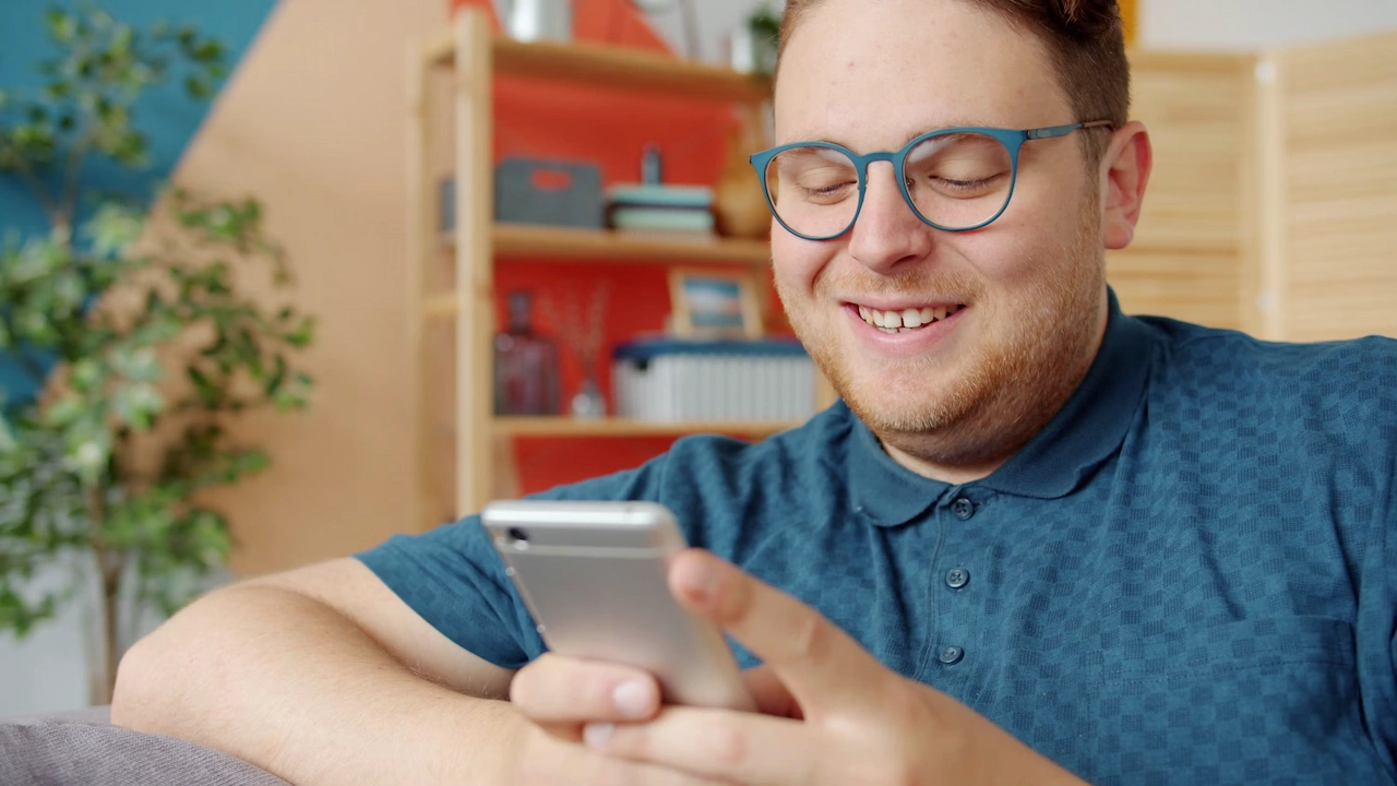Persona sonriendo mientras ve su celular